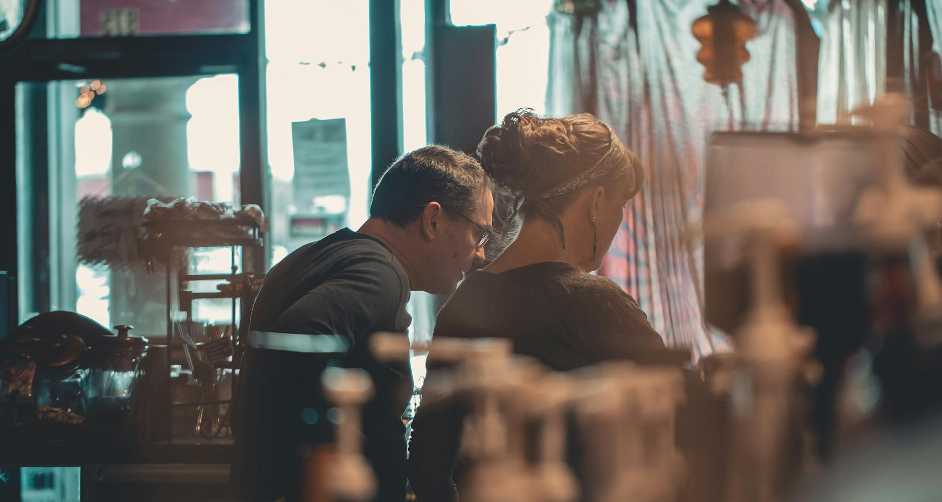 Two small business owners engaged in conversation within a warm, inviting cafe setting.